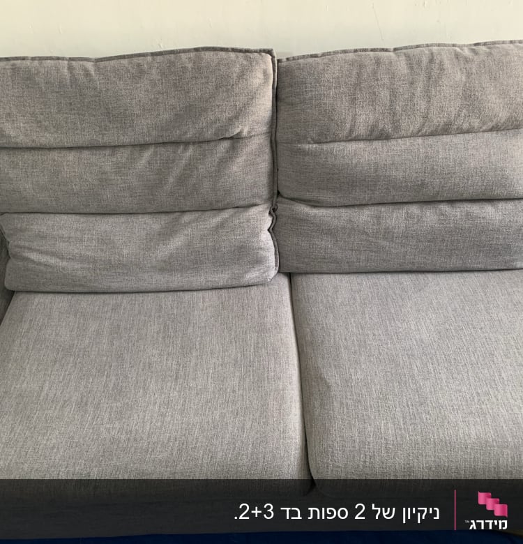 ספה אפורה נקייה על רקע קיר לבן